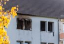 Brandbeschädigte Fenster und Fassade des Mehrfamilienhauses in Calau bei Tageslicht.