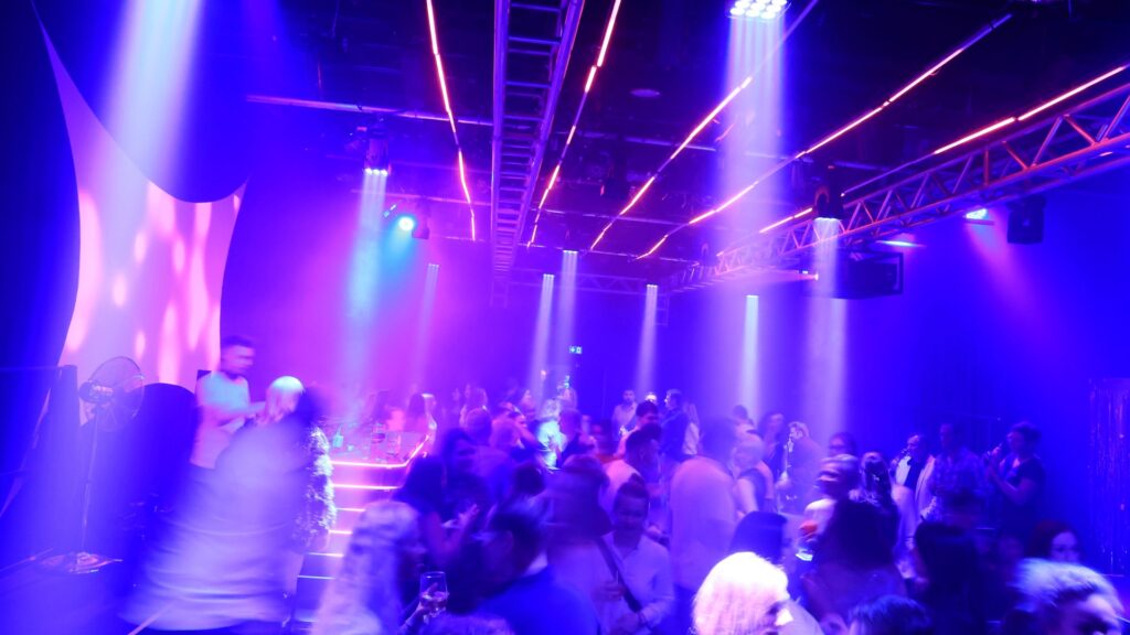 Gäste einer früheren nB ClubNacht unter farbiger Beleuchtung im Theaterstudio.