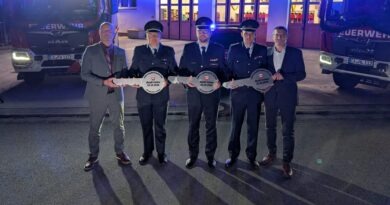 Vertreter der Stadt und Feuerwehr Calau sowie des Landes bei der symbolischen Schlüsselübergabe vor den Einsatzfahrzeugen.