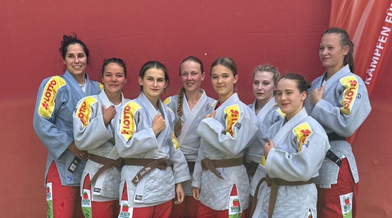 Die Frauenmannschaft von KSC ASAHI Spremberg vor einer roten Wand